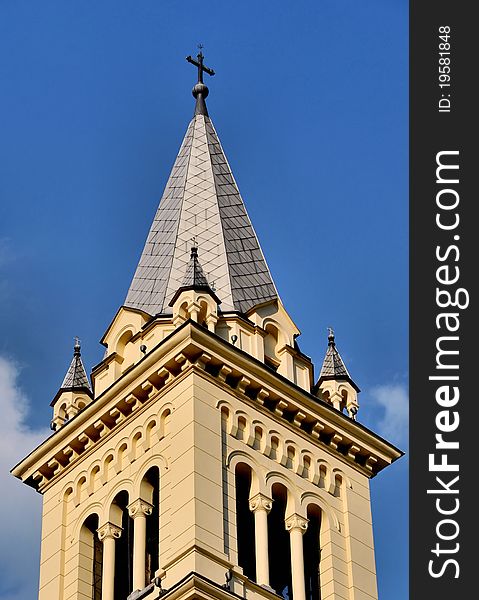 A cross on top of a church against blue sky with a few clouds - copy space. A cross on top of a church against blue sky with a few clouds - copy space