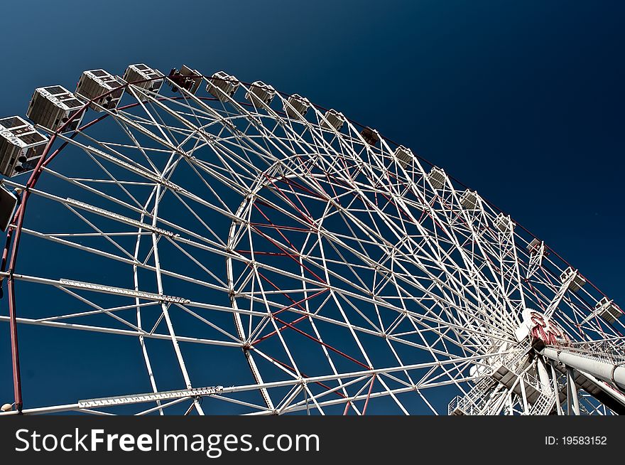 White ferris wheel against a deep blue sky