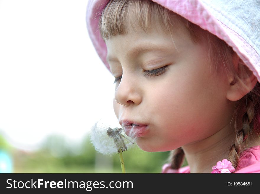 Beautiful little girl on a lawn with dandelions