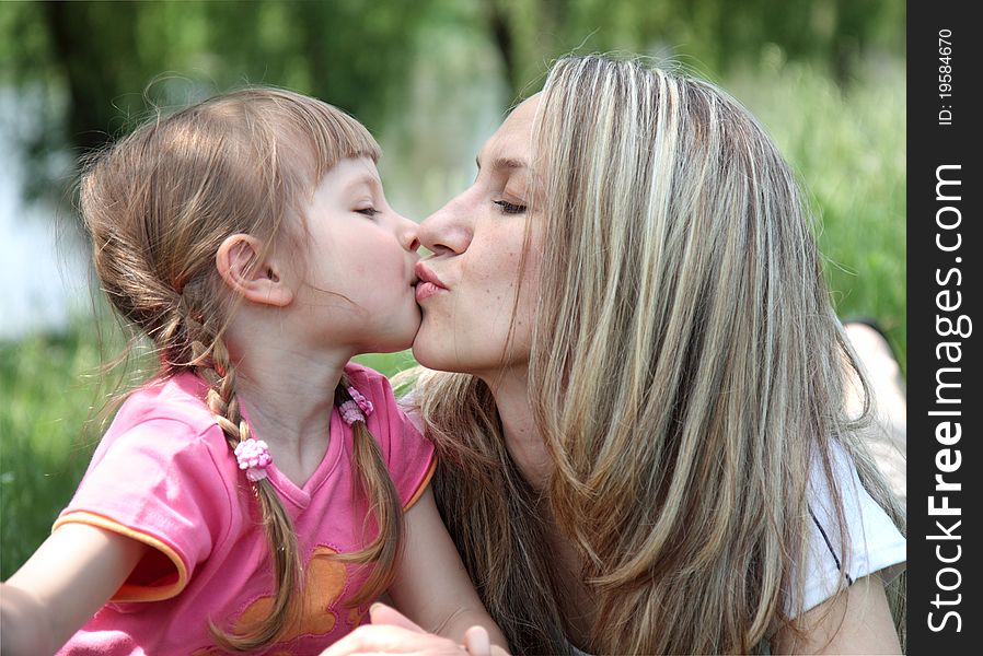 Little girl kissing her mother in a park