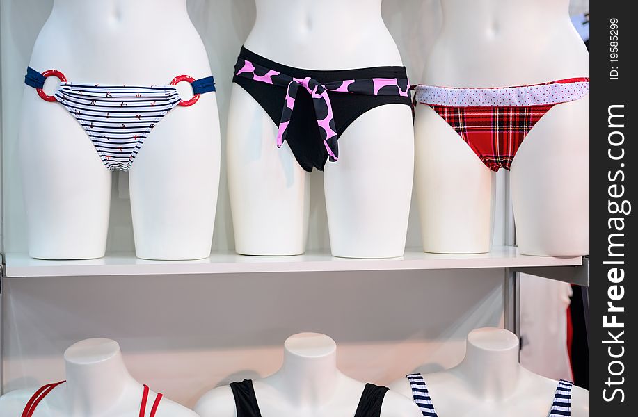 Mannequins with swimsuits stand on a shelf. Mannequins with swimsuits stand on a shelf.