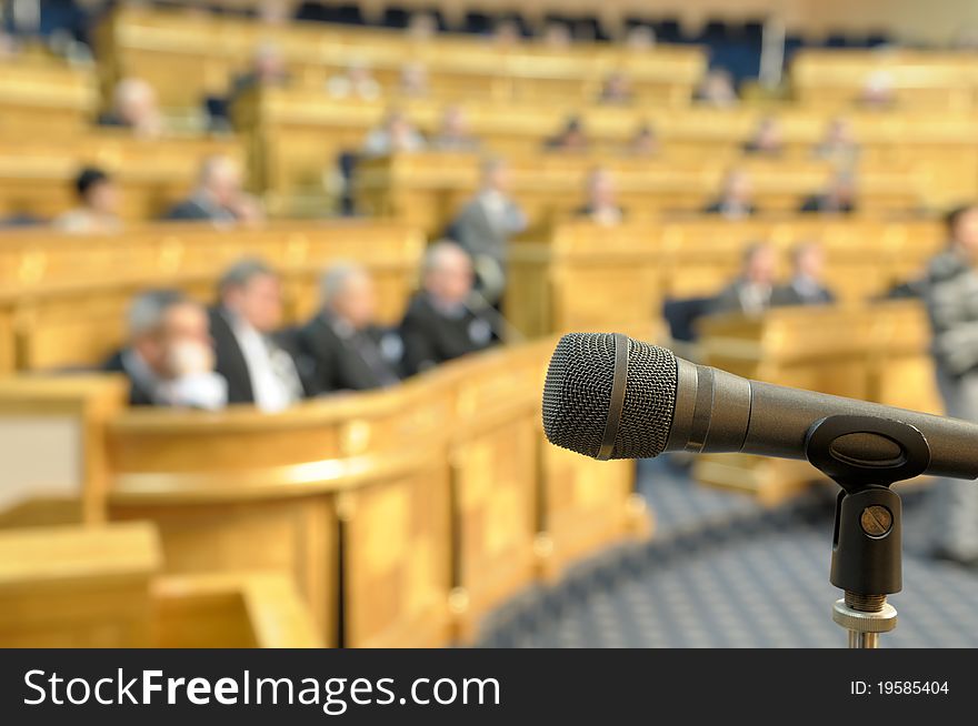 Microphone on a stand against the background of unrecognizable people at conference hall. Microphone on a stand against the background of unrecognizable people at conference hall.