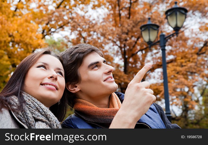 Happy young couple in autumn park, man pointing up. Happy young couple in autumn park, man pointing up