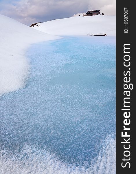 A small icy mountain lake after a frozen winter night. Brixia province, Lombardy region, Italy. A small icy mountain lake after a frozen winter night. Brixia province, Lombardy region, Italy