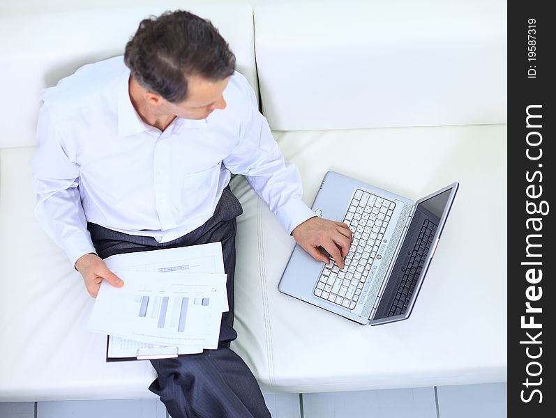 Senior businessman sitting on sofa and using laptop