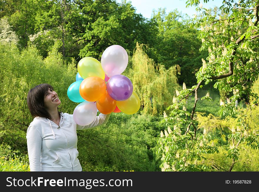 Holiday.Woman with color balloons against a blossoming trees. Holiday.Woman with color balloons against a blossoming trees