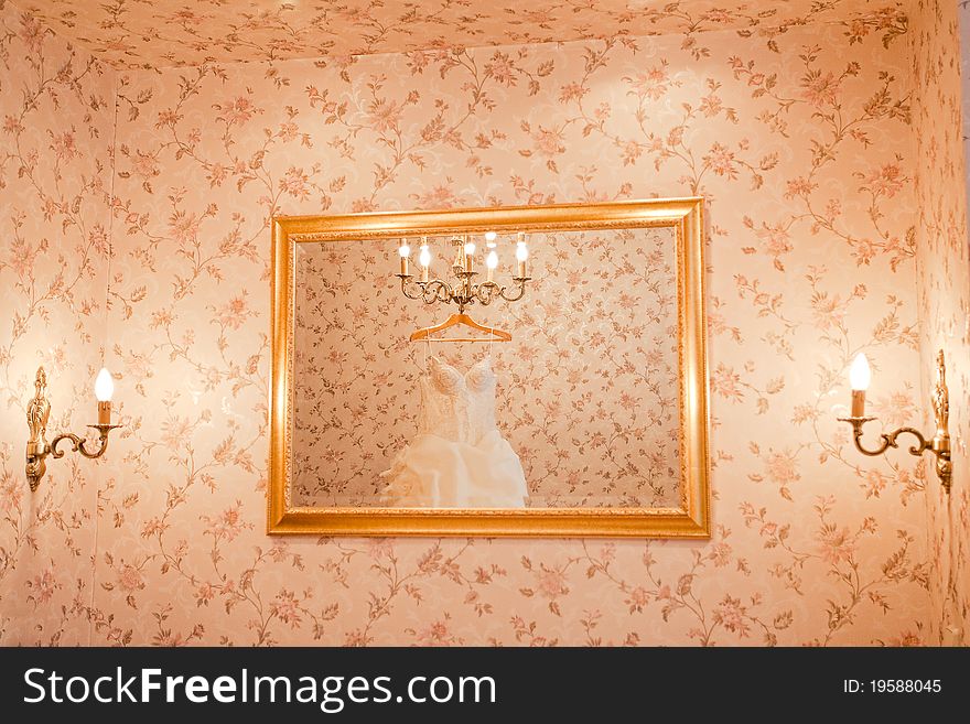 White wedding dress is reflecting in the mirror on the wall. White wedding dress is reflecting in the mirror on the wall