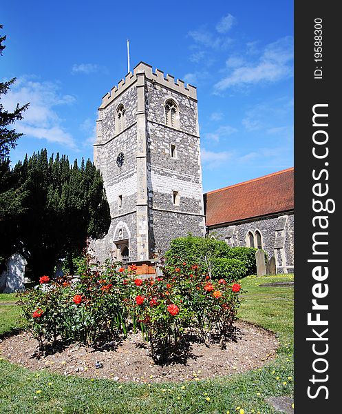 English Village Church and Tower with a flowerbed of Red Roses in the foreground. English Village Church and Tower with a flowerbed of Red Roses in the foreground