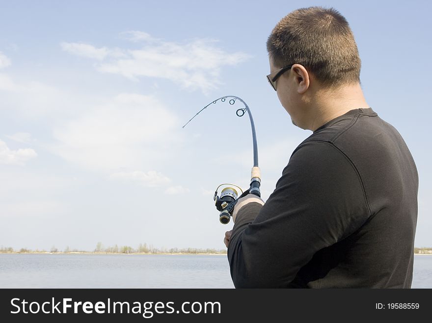 Fisherman holding a spinning rod. fishing on the lake