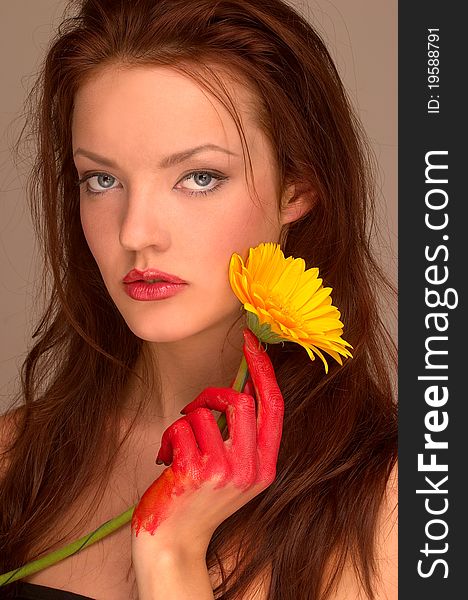 A portrait of a pretty female painter holding a yellow gerbera in her hand. A portrait of a pretty female painter holding a yellow gerbera in her hand.