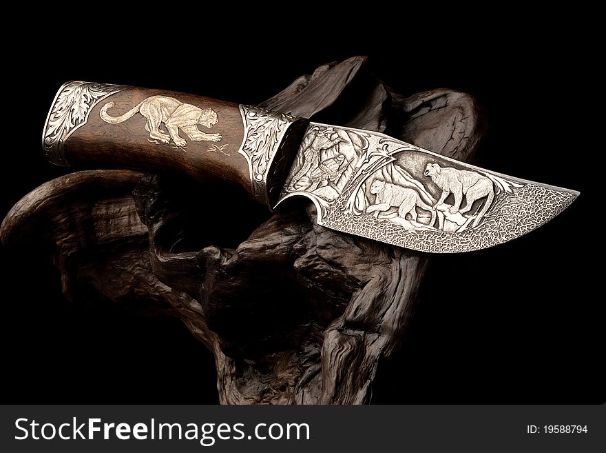 Details of elaborate wildlife and decorative designs on an ornamental hunting knife.