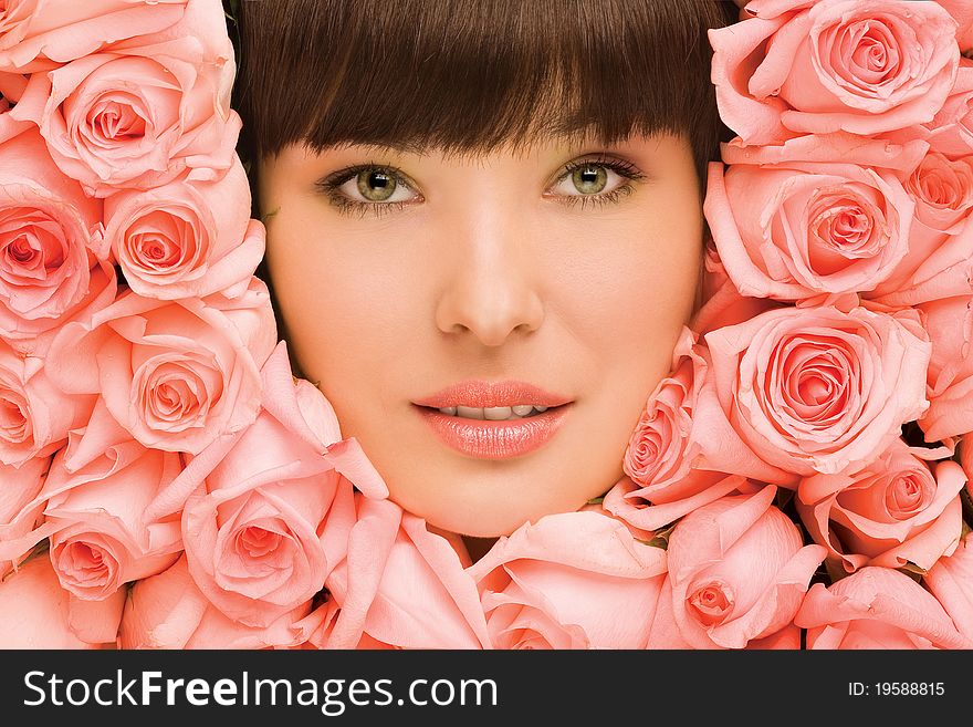 A portrait of a pretty girl's face in pink roses. A portrait of a pretty girl's face in pink roses.