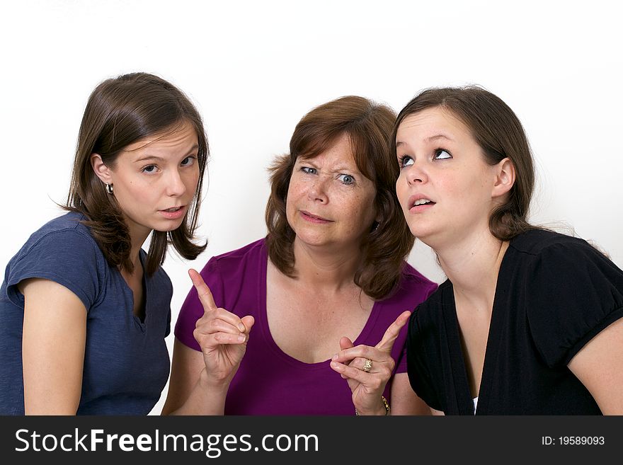 Mother pointing fingers at her daughters with silly expression. Mother pointing fingers at her daughters with silly expression.