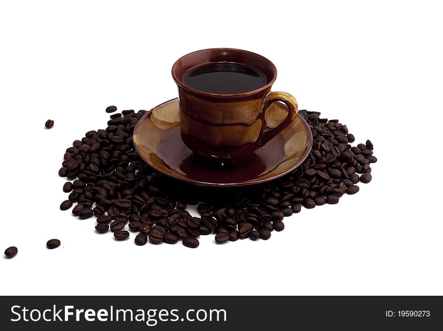 Cup of coffee standing on grains on white background