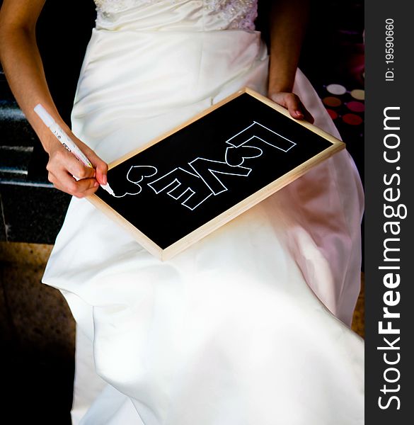 A photo showing the bride writing the word love on a chalkboard.