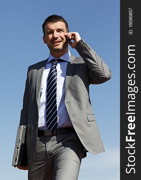 Young businessman with phone and blue sky. Young businessman with phone and blue sky