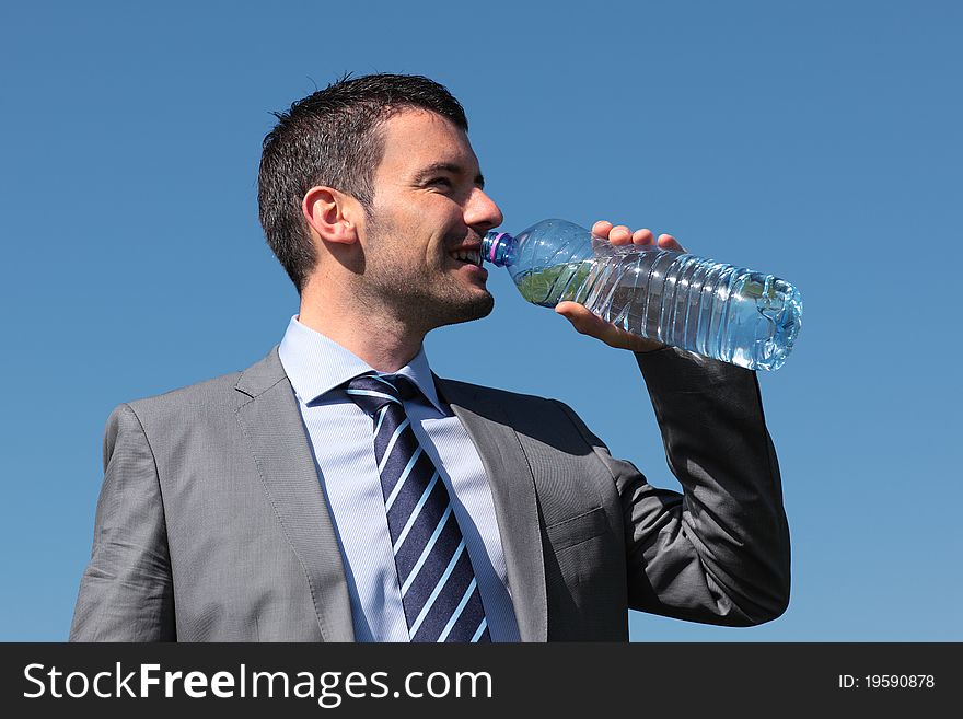 Businessman drinking water with bottle and blue sky