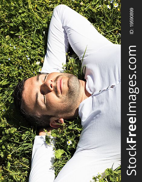 Young man sleeping on the grass in summer