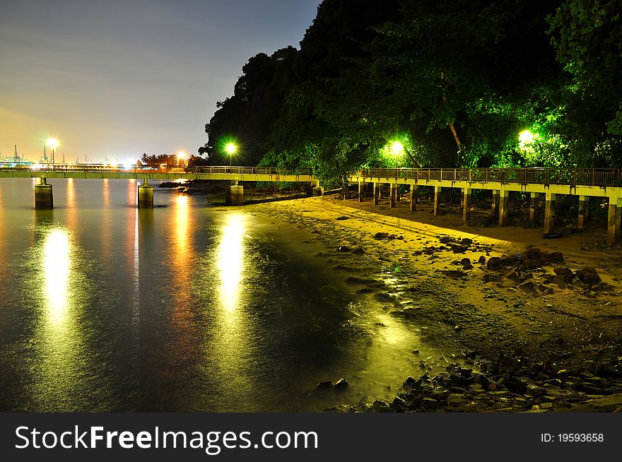 A Jetty at stony beach with lights reflection on the water in Labrador Park, Singapore. A Jetty at stony beach with lights reflection on the water in Labrador Park, Singapore