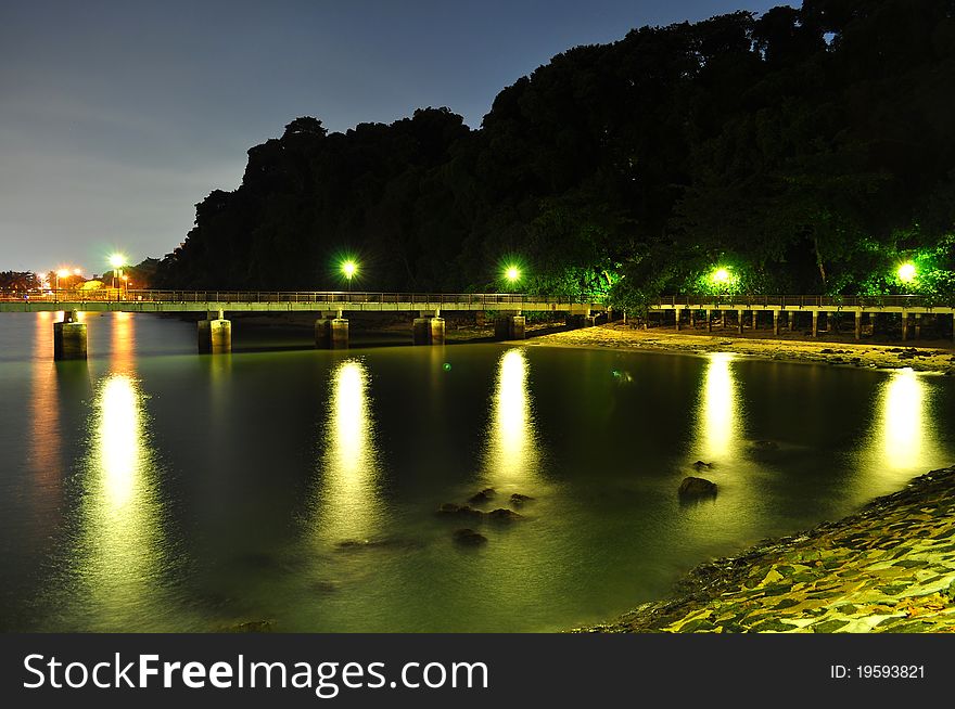 A Lighted Jetty With Dark Trees Background