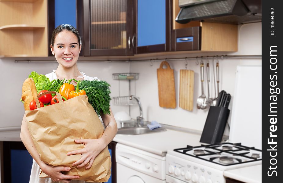 Young beautiful caucasian woman in the kitchen with vegetable