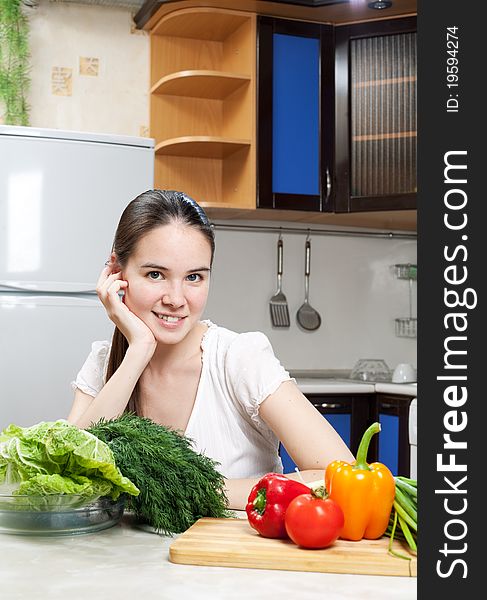 Young beautiful caucasian woman in the kitchen with vegetable