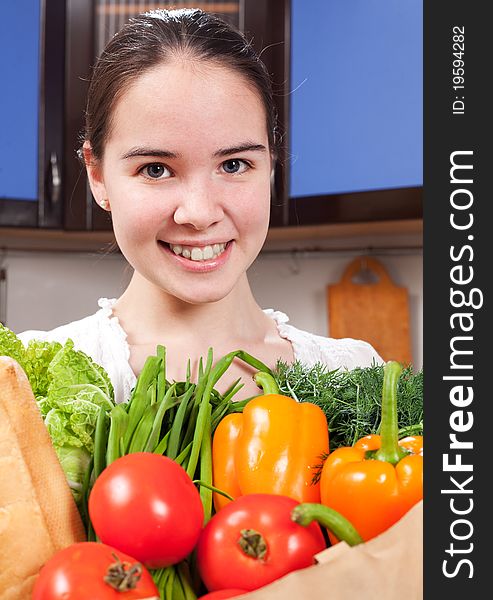 Young beautiful caucasian woman in the kitchen with vegetable