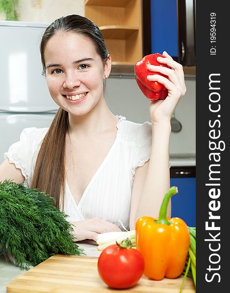 Young beautiful caucasian woman in the kitchen with vegetable