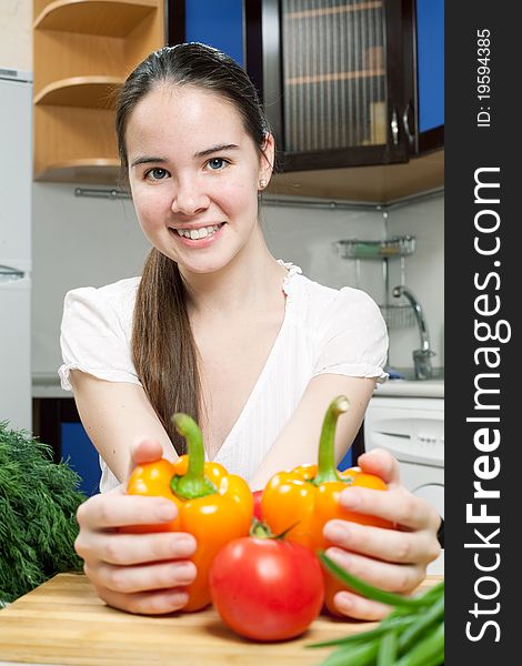 Young beautiful caucasian woman in the kitchen with vegetable