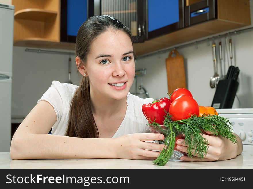 Young beautiful caucasian woman in the kitchen with vegetable