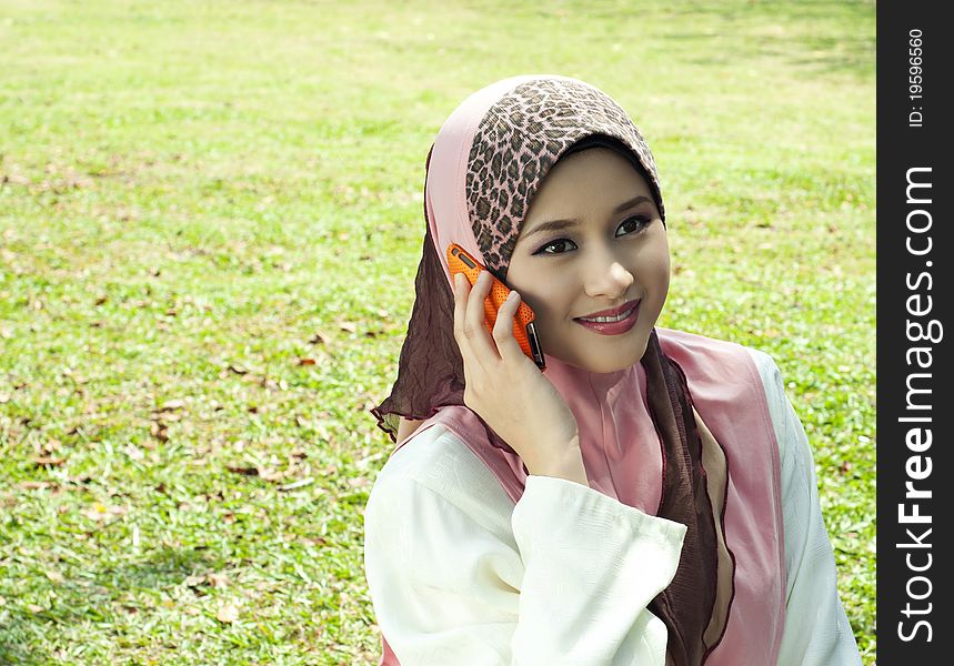 Pretty Muslim girl with a phone at garden