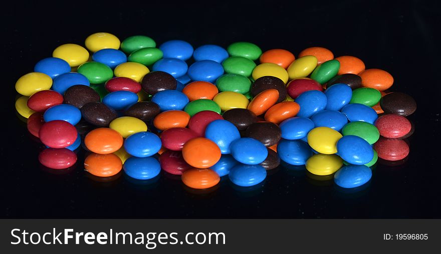 Chocolate glazed multicolored dragee on the black background. Chocolate glazed multicolored dragee on the black background
