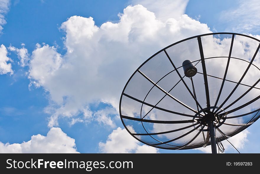 Satellite dishes under a black sky and fluffy clouds. Satellite dishes under a black sky and fluffy clouds
