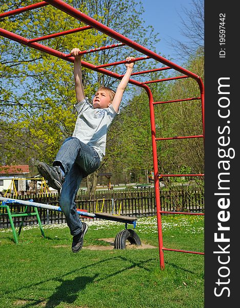 Blond boy climbs on a jungle gym, on a playground. Blond boy climbs on a jungle gym, on a playground.