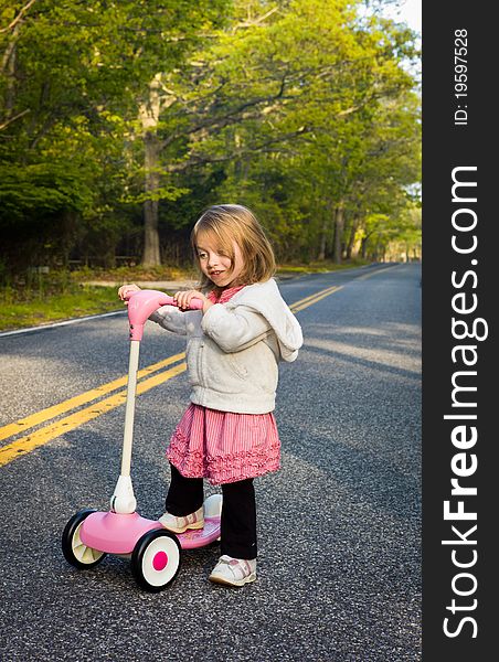 Little Girl Riding a Pink Scooter