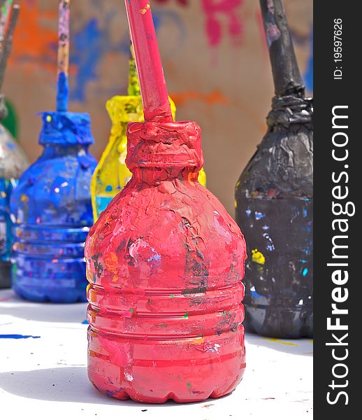 Red, blue, black and yellow paint in the water bottles with brushes. At the food festival - children painting.