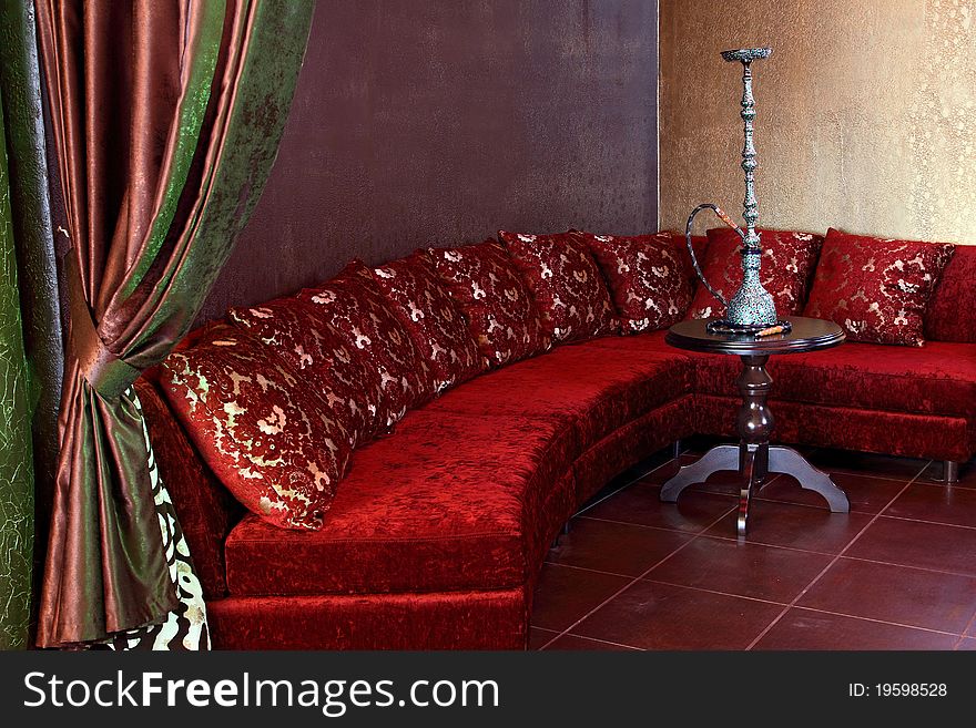Room with a sofa, with pillows and a little table with a beautiful hookah.