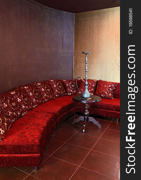 Room with a sofa, with pillows and a little table with a beautiful hookah.