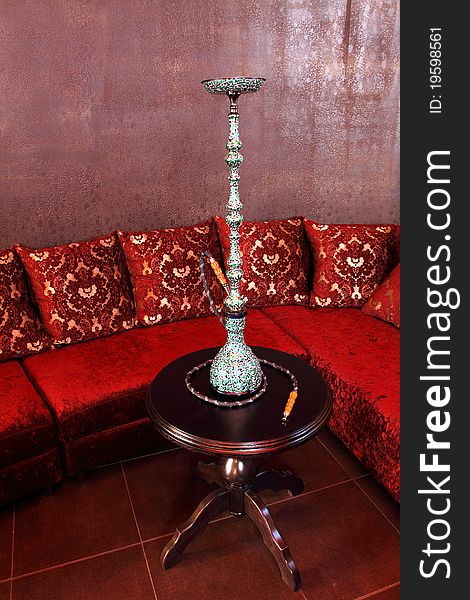 Room with a sofa, with pillows and a little table with a beautiful hookah.