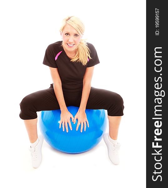A young female dressed in gym clothes sat on a blue gym ball on isolated white background. A young female dressed in gym clothes sat on a blue gym ball on isolated white background