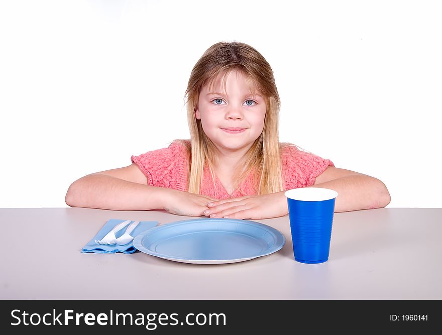 Young girl sitting at table with party type plastic plate, cup, and utensils. Young girl sitting at table with party type plastic plate, cup, and utensils.