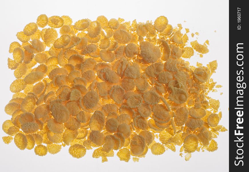 Scattered yellow corn flakes on the white surface