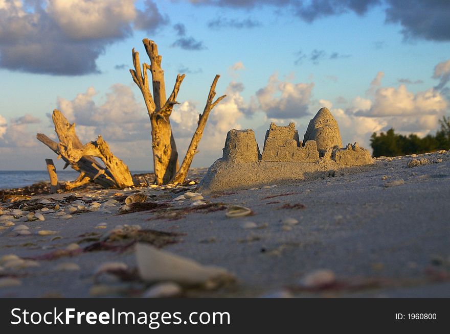 The early morning sun greets someone's leftover sandcastle - very low angle view. The early morning sun greets someone's leftover sandcastle - very low angle view