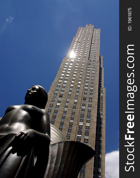 Partial view of a skyscraper with a monument infront in New York City by day, United States, America. Partial view of a skyscraper with a monument infront in New York City by day, United States, America