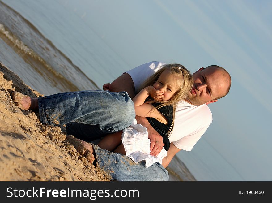 Three and half years old child and her dad sitting on a beach beside ocean. Three and half years old child and her dad sitting on a beach beside ocean.