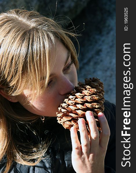 Young woman smelling a pine cone. Young woman smelling a pine cone