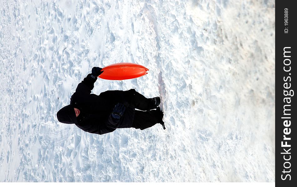 Teen boy climbing back up a snow covered hill with a sled. Teen boy climbing back up a snow covered hill with a sled