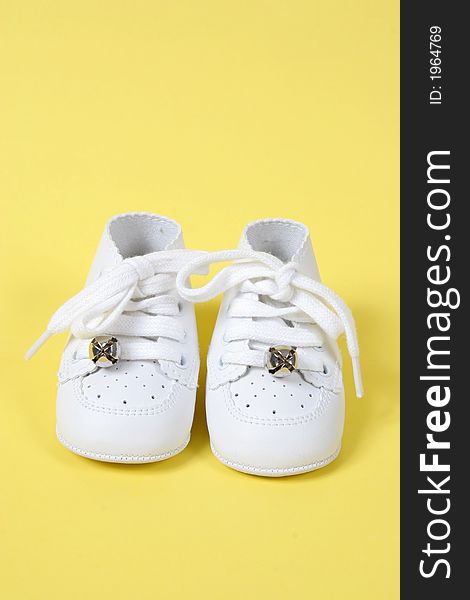 Baby shoes together on yellow background