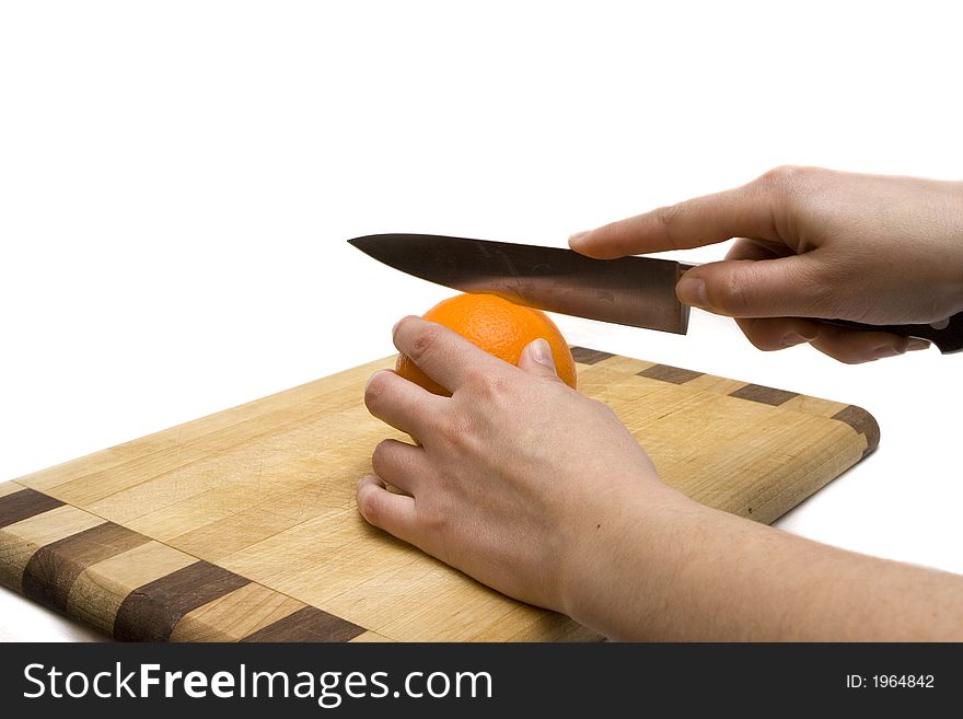Cotting a orange with a kitchen's knife over a wooden table. Cotting a orange with a kitchen's knife over a wooden table
