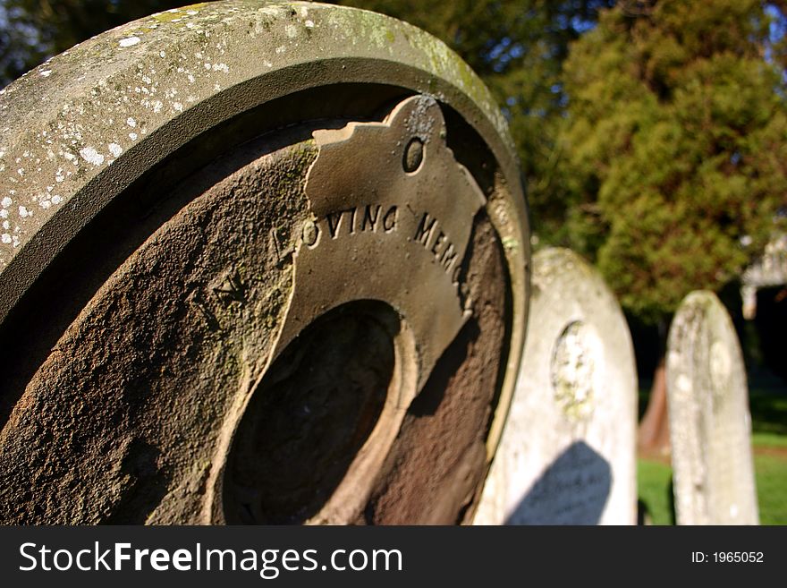 Memories fade - shallow dof focus on tombstone wording in loving memory which are half falling away through neglect and erosion